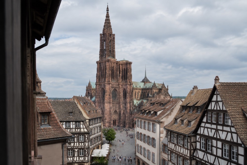 Sunlit rooftops and a single cathedral spire seen from above in summer
