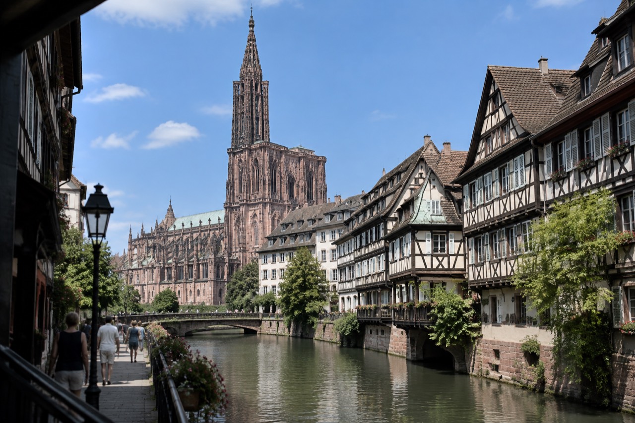 Half-timbered houses along a canal in Strasbourg under a clear blue summer sky