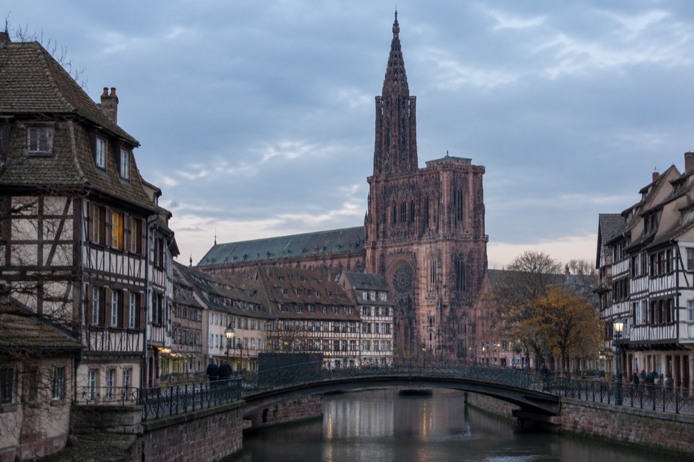 Half-timbered buildings along a canal in Strasbourg with a footbridge in the foreground