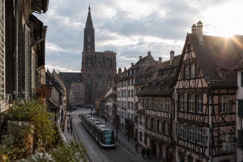 A tram moving along a street in central Strasbourg with the cathedral visible in the distance