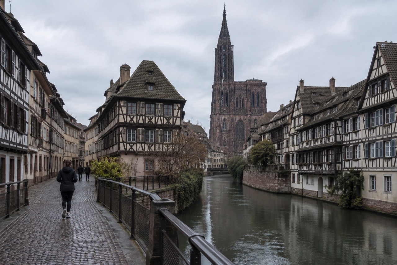 Half-timbered buildings along a canal in Strasbourg with a footbridge in the foreground