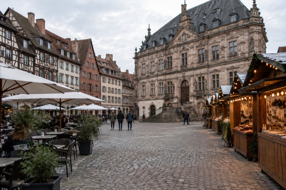 Wooden market stalls with glowing lights along a cobbled street in the evening