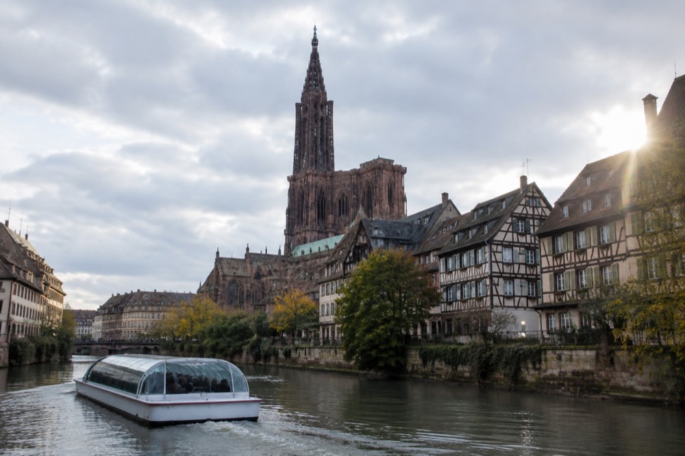 A passenger boat passing half-timbered houses along the River Ill in Strasbourg