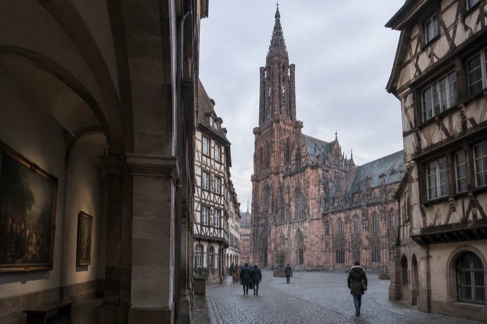 A quiet museum gallery in Strasbourg with stone arches and paintings on the walls