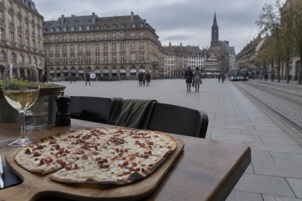 A tarte flambée served on a wooden board in an Alsatian restaurant
