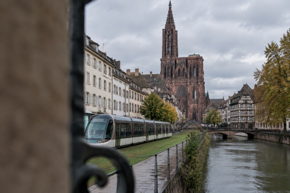 A modern tram gliding along a grass-covered track past pale apartment facades in central Strasbourg
