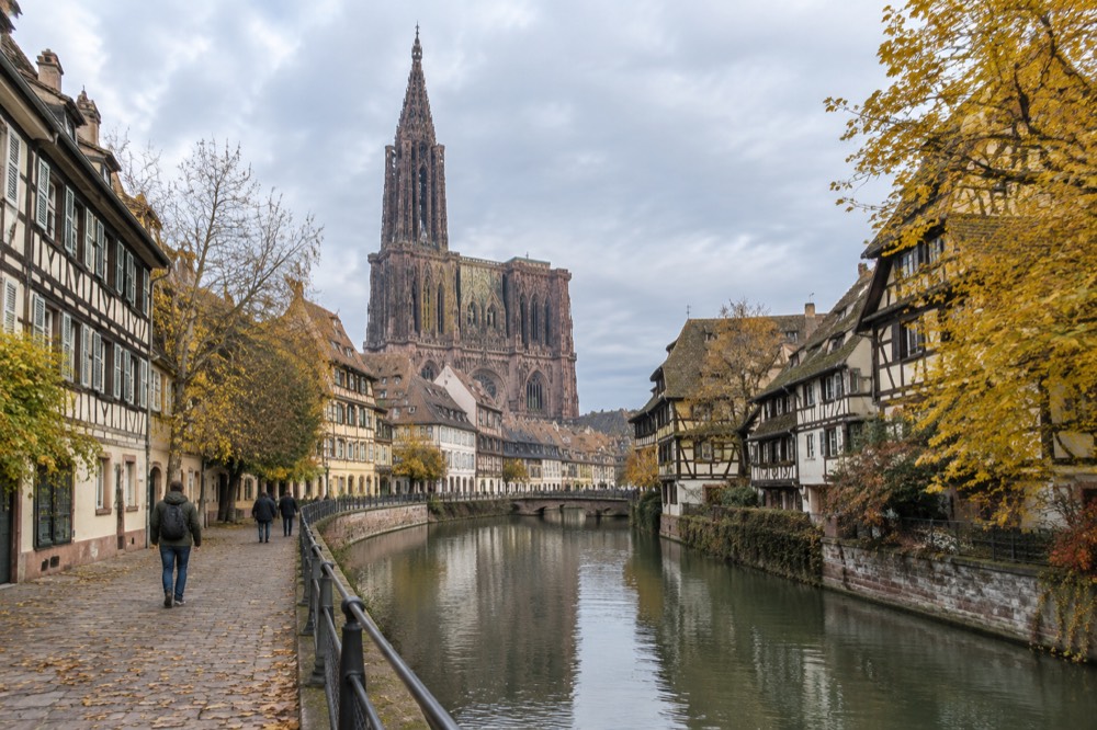 A quiet Strasbourg canal in autumn with golden leaves on the half-timbered buildings