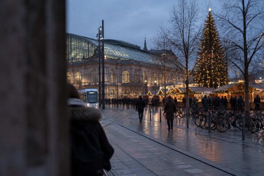 A Christmas market square after dark with illuminated chalets and a large decorated tree