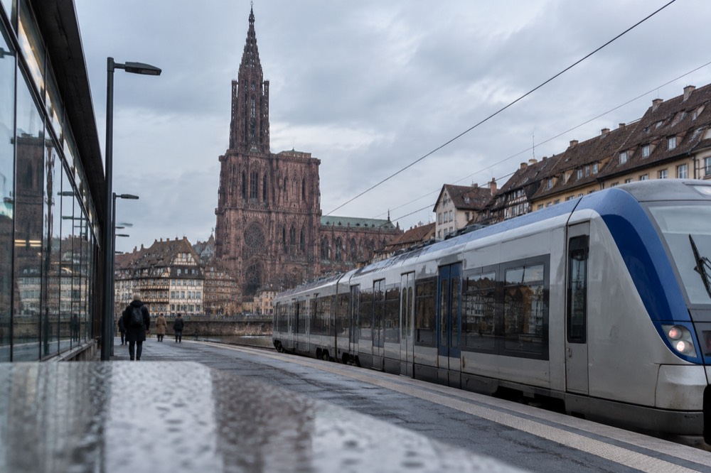 A regional train waiting at a platform beside the glass facade of Strasbourg station