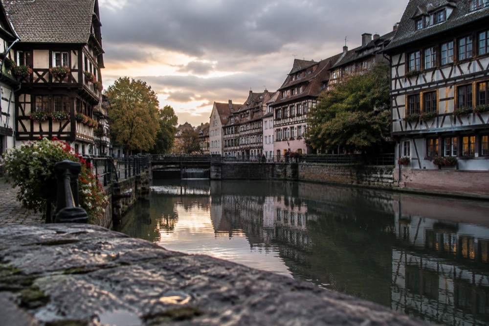 A quiet canal in Petite France at dusk with timber-framed buildings reflected in the water