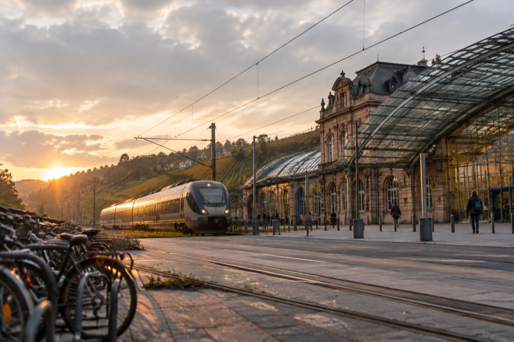 A regional train travelling through rolling countryside with vineyards on the hillsides