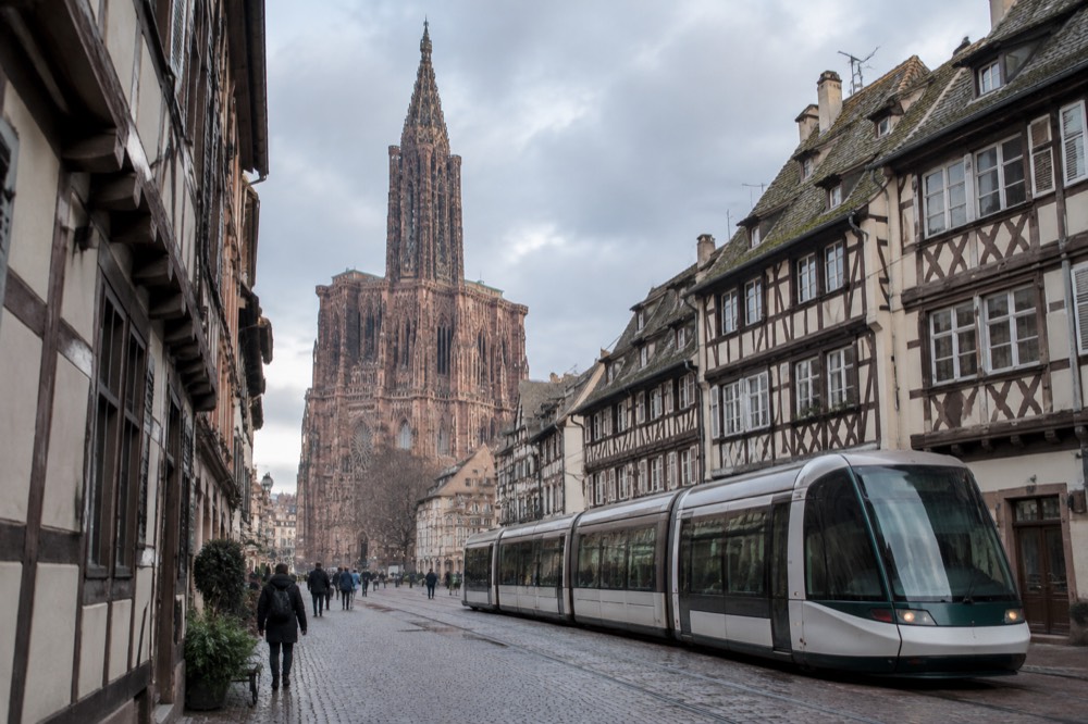 A modern tram passing half-timbered buildings on a street in central Strasbourg