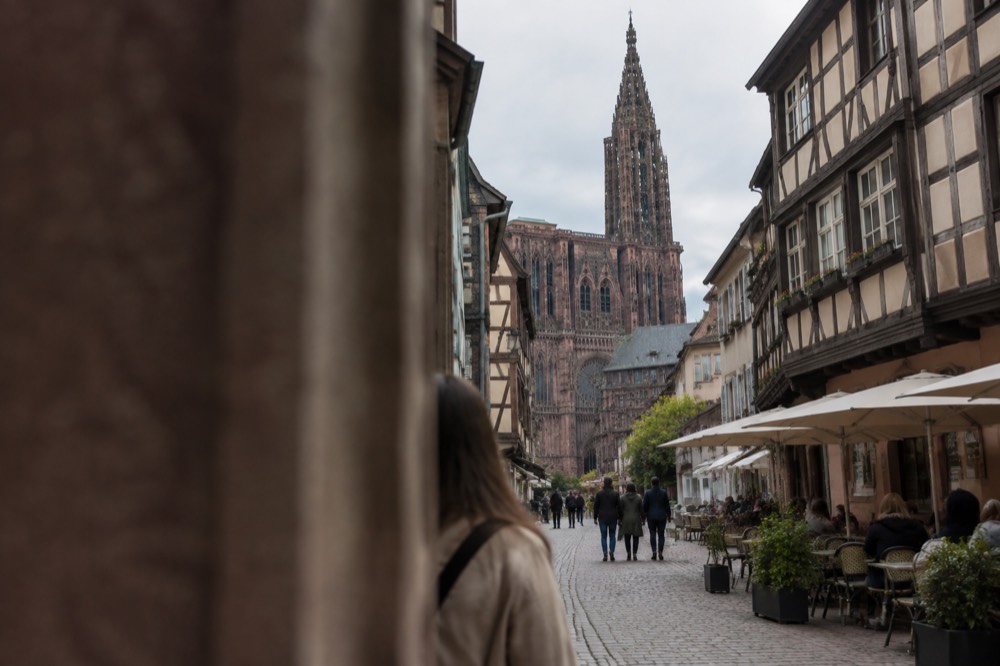 A narrow street of half-timbered buildings with shops and cafés in central Strasbourg