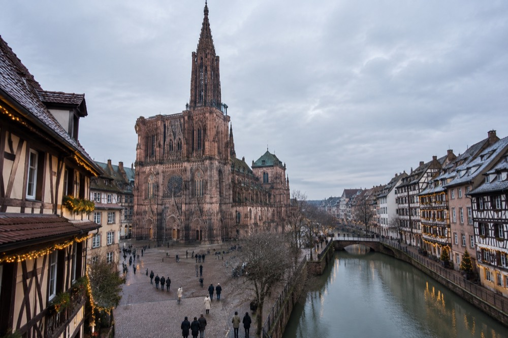 Half-timbered buildings decorated with Christmas lights along a canal in Strasbourg at dusk