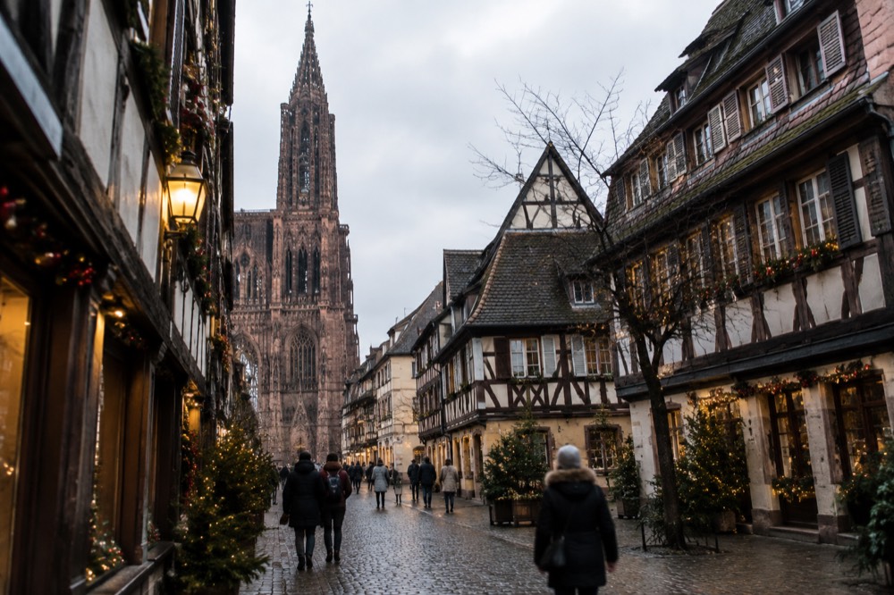 A narrow cobbled street of half-timbered houses decorated for Christmas in Strasbourg