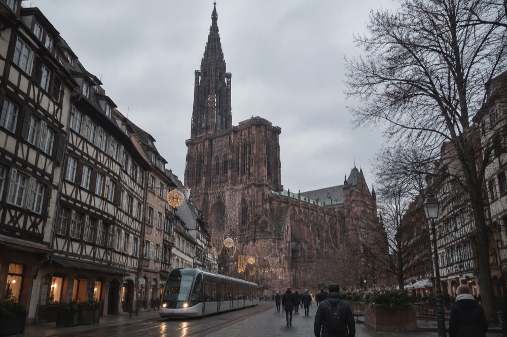 A tram passing illuminated Christmas decorations on a street in central Strasbourg