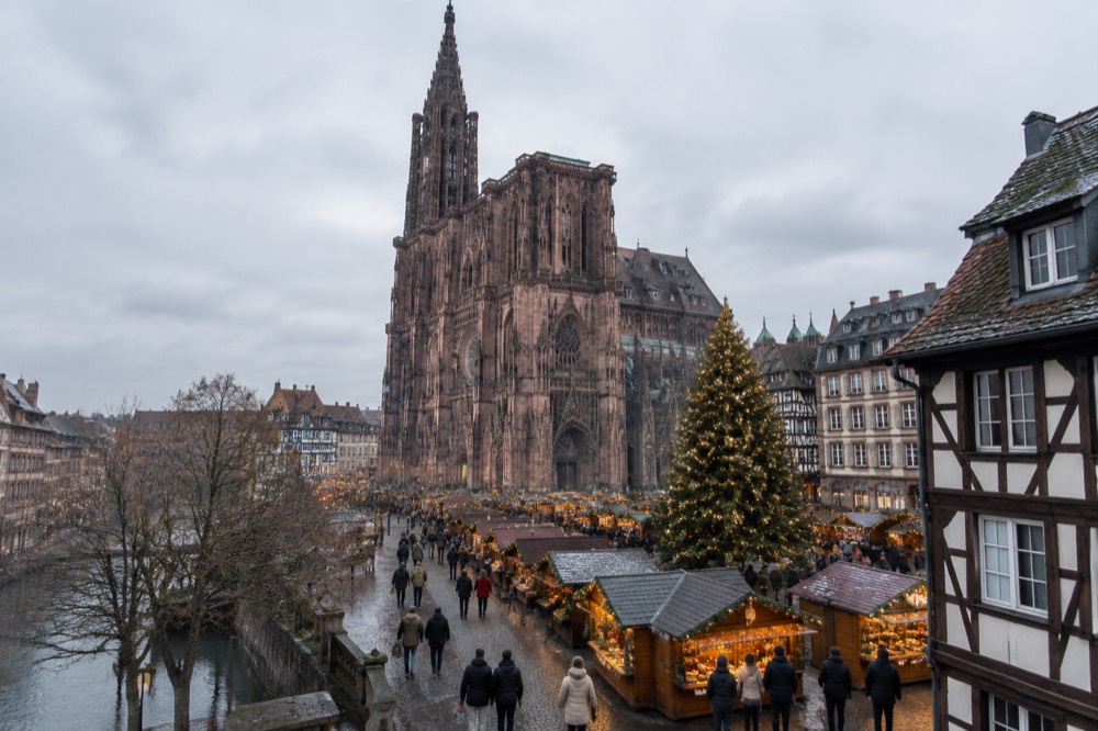 A illuminated Christmas market chalet street with a decorated tree in Strasbourg