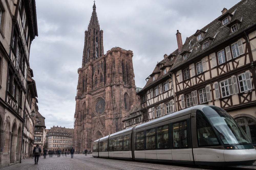 A modern tram passing in front of half-timbered buildings on a Strasbourg street