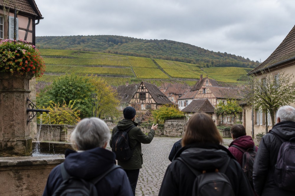 A guide leading a small walking group through a village square