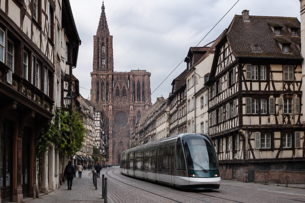 A tram gliding past half-timbered buildings on a Strasbourg street