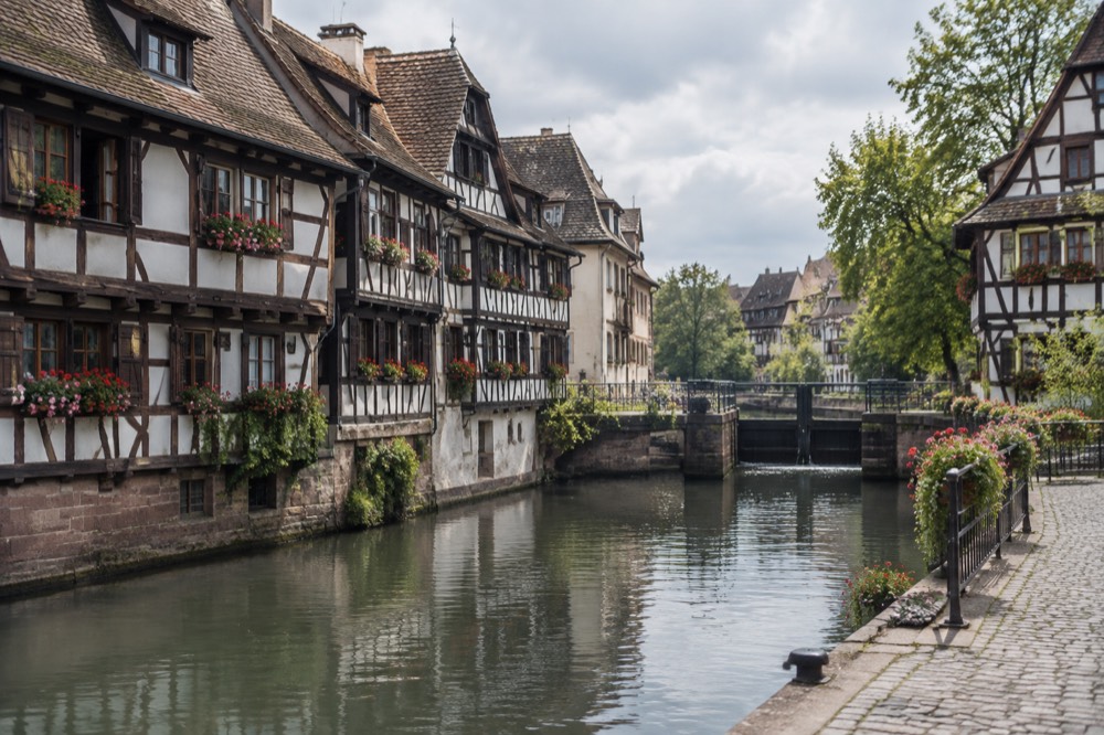Half-timbered houses with flower boxes along a calm canal in Petite France