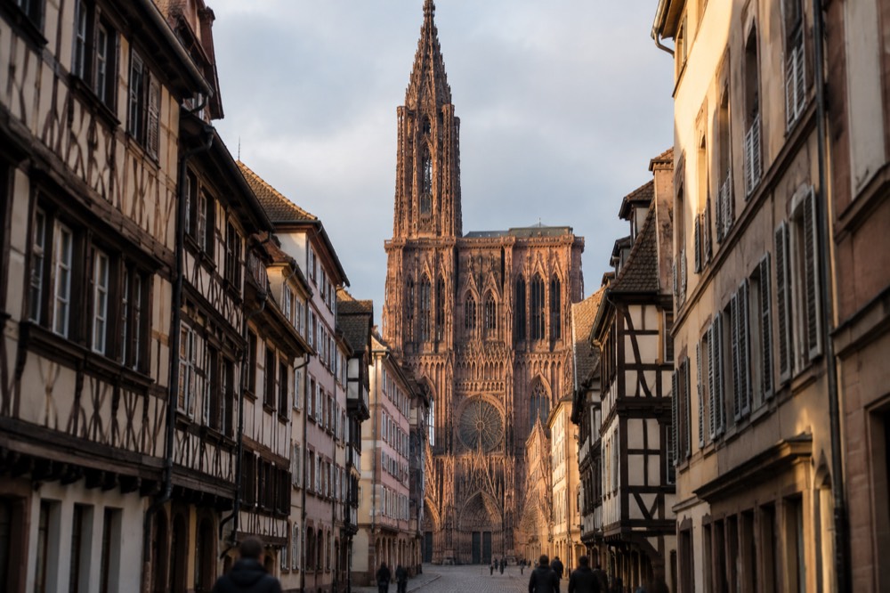 The pink sandstone facade of Strasbourg Cathedral seen from a narrow square