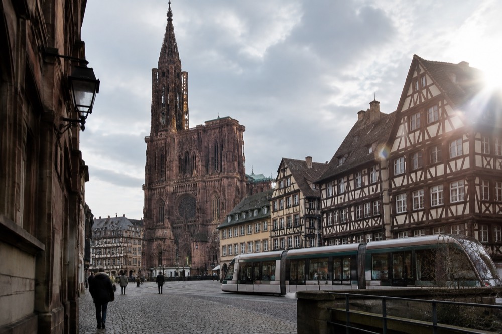 A modern Strasbourg tram passing in front of half-timbered buildings