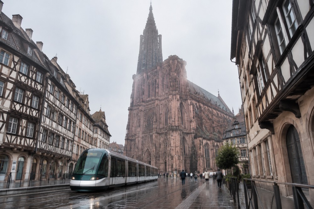 Modern Strasbourg tram at a wet platform with reflections on the rails