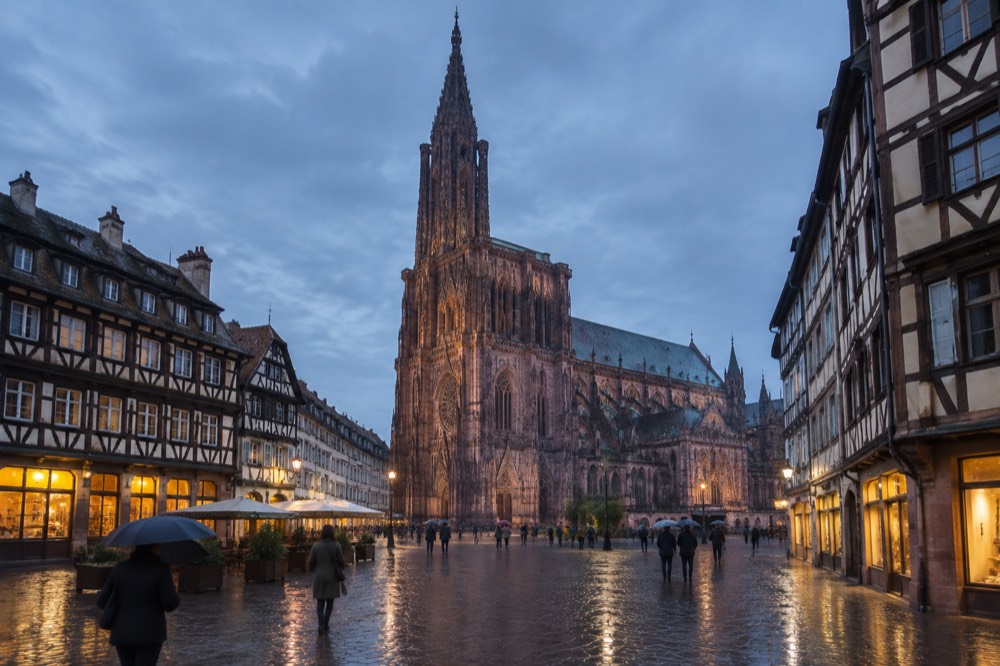 Rainy evening on a Strasbourg square with glowing shop windows and wet paving