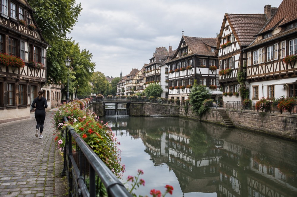 Flower-lined canal in Petite France with old timber buildings reflected in still water