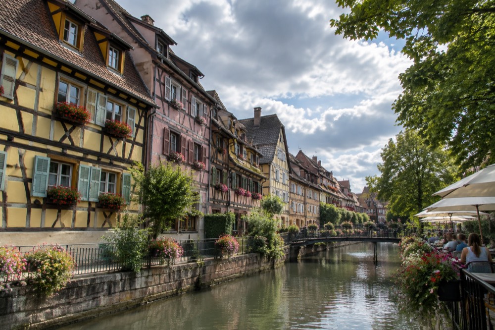 Summer terrace beside the Ill river with trees and old buildings along the bank