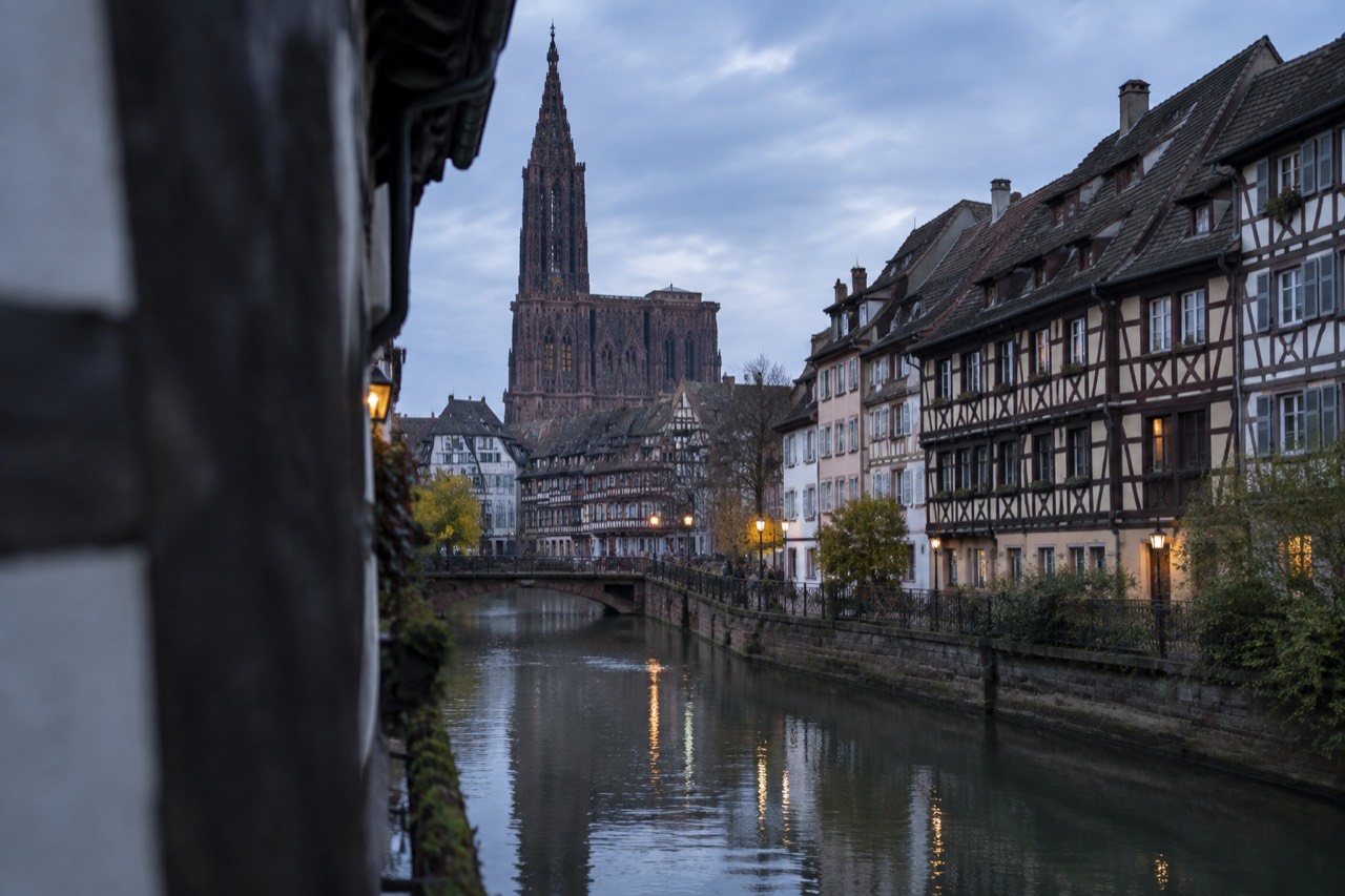 Half-timbered houses along a canal in Strasbourg with the cathedral spire in the distance