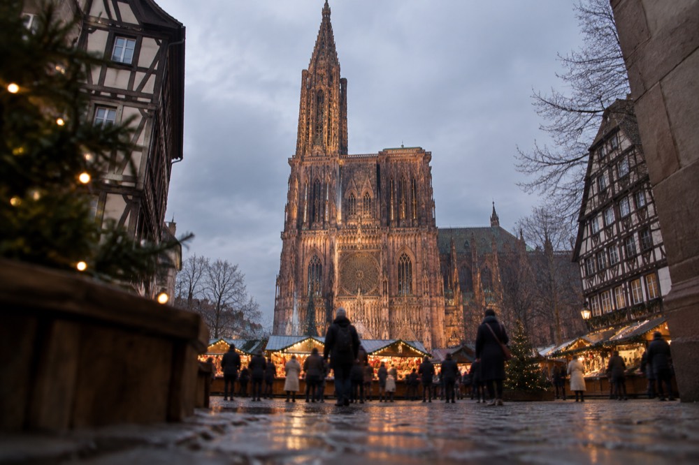 The lit facade of Strasbourg Cathedral above a Christmas market at night