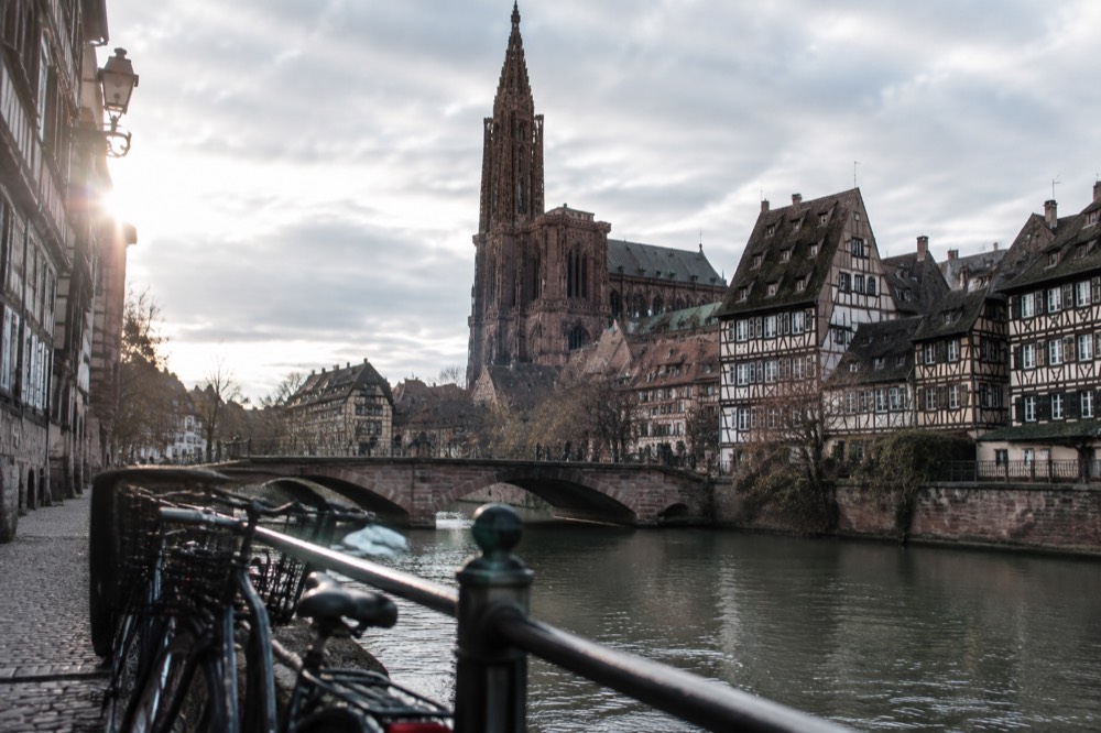 Bicycles parked beside the River Ill near a stone bridge in Strasbourg
