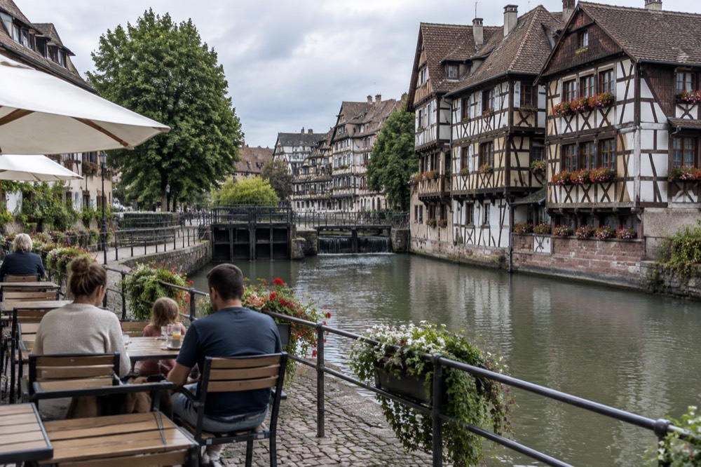 A family sitting at an outdoor café in Petite France with canal views