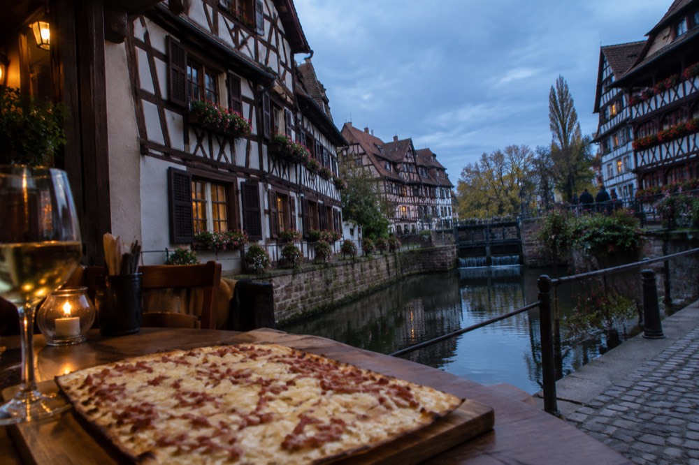 A tarte flambée served on a wooden board in an Alsatian winstub